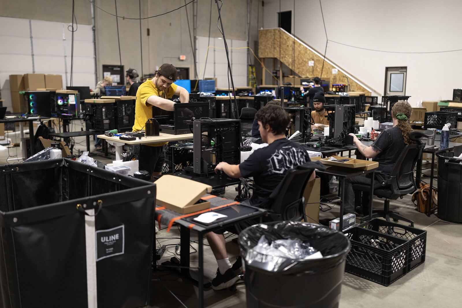 Wide view of the build floor at 80 N Danebo with technicians at standing benches and machines under test.
