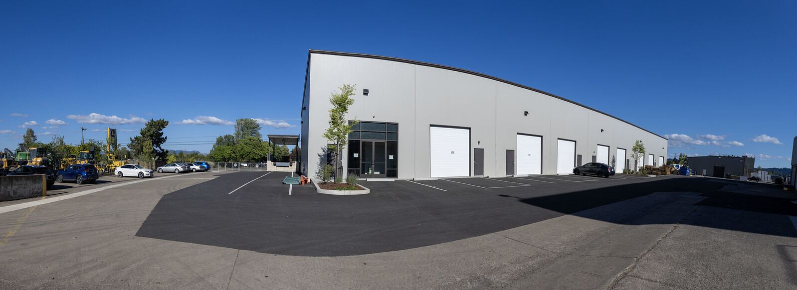 The building at 80 N Danebo Avenue seen across the parking lot: a long single-storey concrete tilt-up with white roll-up bay doors.